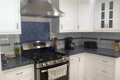 Mid-sized trendy kitchen photo in Los Angeles with white cabinets, granite countertops, white backsplash, ceramic backsplash and stainless steel appliances