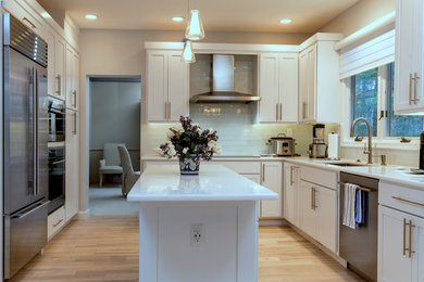 Inspiration for a mid-sized transitional u-shaped medium tone wood floor and gray floor eat-in kitchen remodel in Boston with an undermount sink, shaker cabinets, white cabinets, marble countertops, glass tile backsplash, stainless steel appliances, an island and white countertops