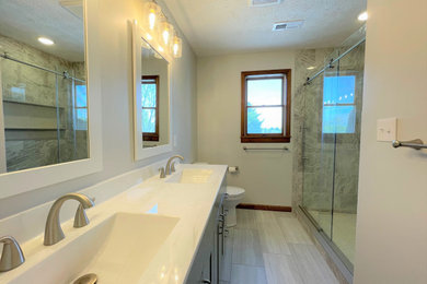 Mid-sized minimalist master gray tile and porcelain tile vinyl floor, gray floor and double-sink bathroom photo in Other with shaker cabinets, gray cabinets, a two-piece toilet, white walls, an integrated sink, marble countertops, white countertops, a niche and a built-in vanity