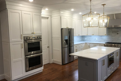 Inspiration for a mid-sized traditional l-shaped kitchen pantry in Boston with an undermount sink, recessed-panel cabinets, white cabinets, quartz benchtops, white splashback, subway tile splashback, stainless steel appliances, dark hardwood floors and with island.