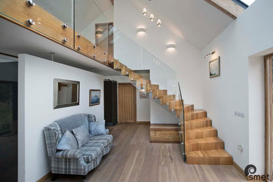 Идея дизайна: угловая деревянная лестница в стиле модернизм с деревянными ступенями и стеклянными перилами