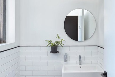 Small transitional white tile and subway tile porcelain tile and black floor powder room photo in New York with a one-piece toilet, white walls and a console sink