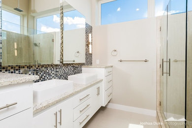 Example of a minimalist master blue tile and glass tile porcelain tile alcove shower design in Other with flat-panel cabinets, white cabinets, beige walls, a vessel sink and granite countertops