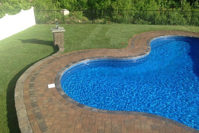 Mid-sized elegant backyard brick and custom-shaped lap pool photo in Providence