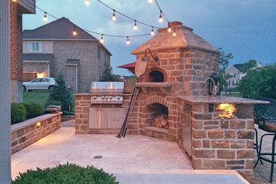 Mid-sized country backyard patio in Cincinnati with an outdoor kitchen, natural stone pavers and a roof extension.