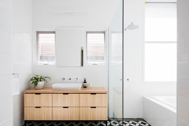 Inspiration for a mid-sized contemporary master bathroom in Melbourne with light wood cabinets, an alcove tub, an open shower, white tile, porcelain tile, mosaic tile floors, wood benchtops, an open shower, flat-panel cabinets, white walls, a vessel sink and multi-coloured floor.