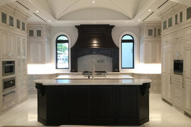 Inspiration for a large timeless u-shaped marble floor and white floor eat-in kitchen remodel in Miami with an undermount sink, raised-panel cabinets, white cabinets, marble countertops, white backsplash, ceramic backsplash, paneled appliances and two islands