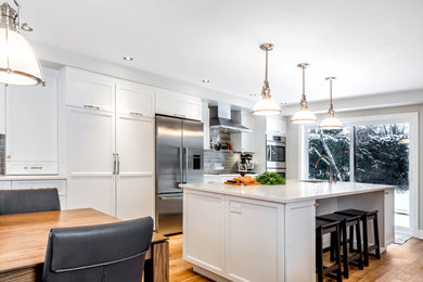 Inspiration for a large transitional single-wall light wood floor eat-in kitchen remodel in Montreal with an undermount sink, recessed-panel cabinets, white cabinets, stainless steel appliances, an island, quartz countertops, gray backsplash and ceramic backsplash