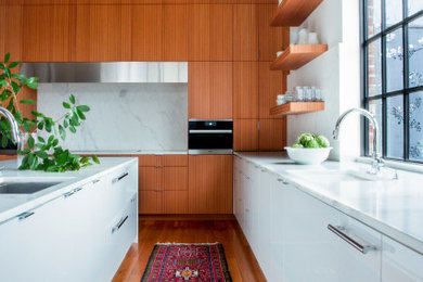 Example of a large minimalist medium tone wood floor and exposed beam eat-in kitchen design in Other with a double-bowl sink, flat-panel cabinets, medium tone wood cabinets, granite countertops, white backsplash, slate backsplash, paneled appliances, an island and white countertops