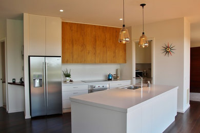 Photo of a mid-sized modern galley open plan kitchen in Melbourne with an undermount sink, flat-panel cabinets, white cabinets, quartz benchtops, white splashback, glass sheet splashback, stainless steel appliances and with island.