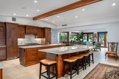 Example of a beach style porcelain tile, beige floor and exposed beam kitchen design in Miami with an undermount sink, louvered cabinets, dark wood cabinets, quartzite countertops, beige backsplash, stone slab backsplash, paneled appliances, two islands and beige countertops