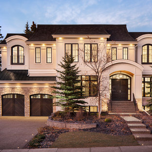 Новый формат декора квартиры: двухэтажный фасад частного дома бежевого цвета в стиле современная классика с облицовкой из цементной штукатурки, мансардной крышей и крышей из гибкой черепицы