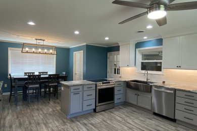 Mid-sized transitional l-shaped porcelain tile enclosed kitchen photo in Other with a farmhouse sink, shaker cabinets, white cabinets, granite countertops, white backsplash, subway tile backsplash, stainless steel appliances, no island and gray countertops