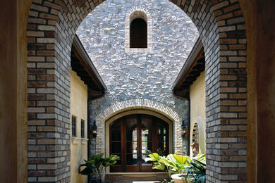Photo of a mid-sized traditional two-storey grey exterior in Miami with stone veneer.