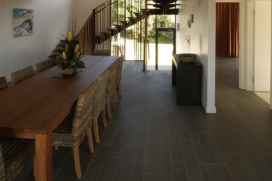 Photo of a large beach style open plan dining in Brisbane with ceramic floors and white walls.