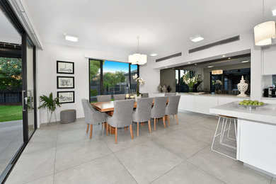 This is an example of a large contemporary kitchen/dining combo in Melbourne with white walls, porcelain floors and grey floor.