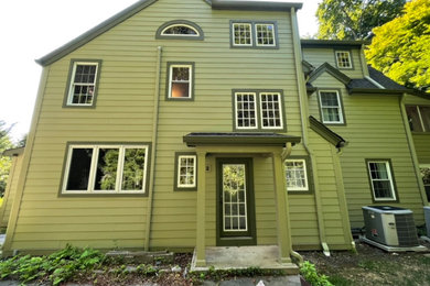 Imagen de fachada de casa verde grande de tres plantas con revestimiento de aglomerado de cemento y tablilla