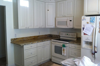 Eat-in kitchen - mid-sized traditional porcelain tile eat-in kitchen idea in Orlando with an undermount sink, raised-panel cabinets, white cabinets, granite countertops, beige backsplash, stone tile backsplash, white appliances and no island