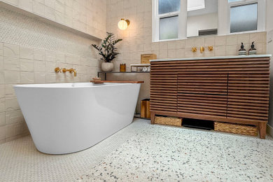 Mid-sized master beige tile and porcelain tile single-sink drop-in bathtub photo in Los Angeles with medium tone wood cabinets, quartzite countertops and white countertops