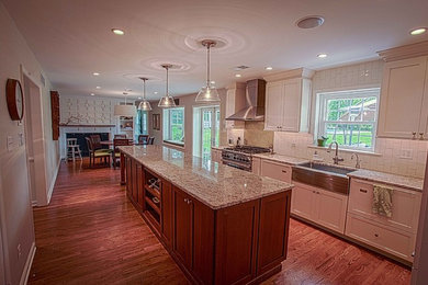 Photo of a large traditional separate kitchen in Denver with a farmhouse sink, shaker cabinets, white cabinets, granite benchtops, white splashback, porcelain splashback, panelled appliances, dark hardwood floors and with island.