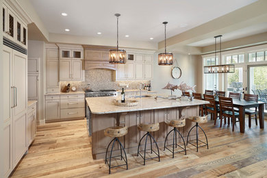 Eat-in kitchen - large traditional l-shaped medium tone wood floor and brown floor eat-in kitchen idea in Edmonton with an undermount sink, recessed-panel cabinets, beige cabinets, quartz countertops, brown backsplash, mosaic tile backsplash, stainless steel appliances, an island and beige countertops