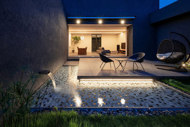 Diseño de patio moderno grande en patio con suelo de baldosas y toldo