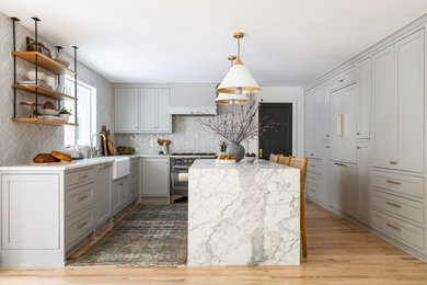 Kitchen - transitional u-shaped light wood floor and beige floor kitchen idea in Seattle with a farmhouse sink, shaker cabinets, gray cabinets, white backsplash, black appliances, an island and white countertops