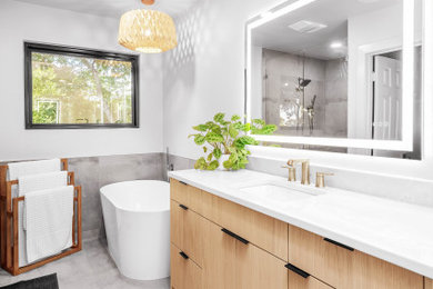 Freestanding bathtub - mid-sized modern gray tile ceramic tile and gray floor freestanding bathtub idea in Austin with flat-panel cabinets, light wood cabinets, gray walls, an undermount sink, quartz countertops, white countertops and a freestanding vanity
