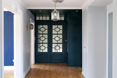 Cette image montre une entrée traditionnelle avec un mur vert, un sol en bois brun et une porte double.