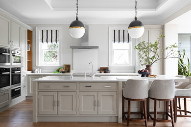 Design ideas for a large classic l-shaped open plan kitchen in Cheshire with shaker cabinets, grey cabinets, engineered stone countertops, white splashback, engineered quartz splashback, stainless steel appliances, porcelain flooring, an island, brown floors, white worktops, a coffered ceiling and feature lighting.