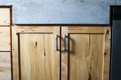 Example of a slate floor eat-in kitchen design in Omaha with a farmhouse sink, light wood cabinets, concrete countertops, glass tile backsplash and stainless steel appliances