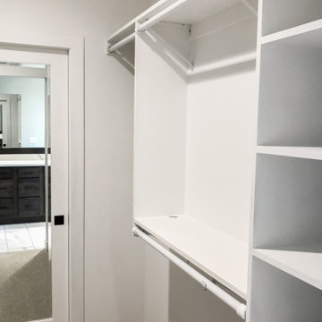 Master closet with custom shelving and hanging space for long items