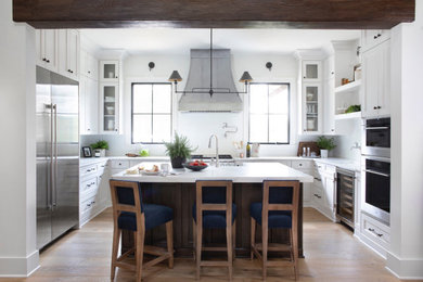 Inspiration for a large country u-shaped open plan kitchen in Atlanta with white cabinets, white splashback, stainless steel appliances, light hardwood floors, with island, white benchtop, shaker cabinets, quartzite benchtops, a farmhouse sink, subway tile splashback and beige floor.
