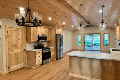 Inspiration for a mid-sized rustic galley light wood floor and vaulted ceiling eat-in kitchen remodel in Minneapolis with an undermount sink, shaker cabinets, light wood cabinets, laminate countertops, stainless steel appliances, a peninsula and white countertops