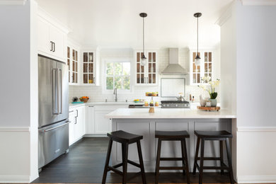 Transitional l-shaped dark wood floor and brown floor kitchen photo in Los Angeles with an undermount sink, shaker cabinets, white cabinets, white backsplash, subway tile backsplash, stainless steel appliances, a peninsula and white countertops