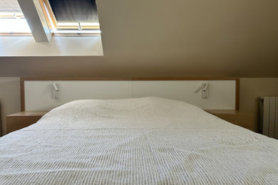 Cette image montre une chambre mansardée ou avec mezzanine blanche et bois minimaliste de taille moyenne avec un mur beige, parquet clair, aucune cheminée, un sol marron et dressing.