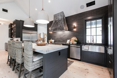 Eat-in kitchen - large contemporary l-shaped light wood floor, beige floor and vaulted ceiling eat-in kitchen idea in Atlanta with a farmhouse sink, flat-panel cabinets, black cabinets, quartzite countertops, black backsplash, subway tile backsplash, black appliances, an island and white countertops