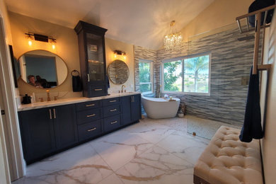 Huge beach style master blue tile and porcelain tile marble floor, white floor, double-sink, vaulted ceiling and wallpaper bathroom photo in Orange County with shaker cabinets, blue cabinets, a two-piece toilet, beige walls, an undermount sink, quartz countertops, white countertops and a built-in vanity