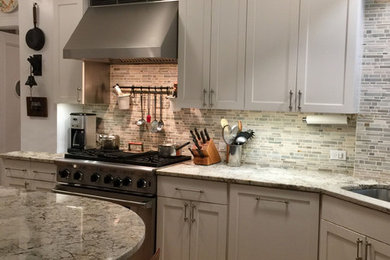 Large transitional galley separate kitchen in New York with an undermount sink, shaker cabinets, white cabinets, granite benchtops, multi-coloured splashback, mosaic tile splashback, stainless steel appliances and cork floors.