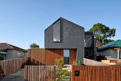Contemporary black house exterior in Melbourne with wood siding, a gable roof and a shingle roof.