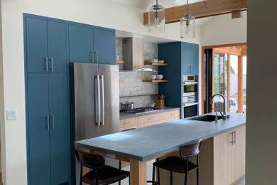 Kitchen - large modern galley concrete floor, gray floor and vaulted ceiling kitchen idea in Other with an undermount sink, flat-panel cabinets, blue cabinets, white backsplash, marble backsplash, stainless steel appliances, an island and gray countertops