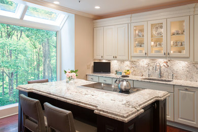 Photo of a large traditional l-shaped eat-in kitchen in DC Metro with granite benchtops, raised-panel cabinets, white cabinets, white splashback, stone slab splashback, stainless steel appliances, dark hardwood floors, with island, an undermount sink and brown floor.