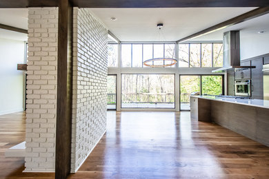 Large trendy l-shaped medium tone wood floor and brown floor kitchen photo in Atlanta with an undermount sink, flat-panel cabinets, dark wood cabinets, stainless steel appliances, an island and white countertops