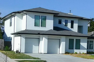 Example of a large trendy white two-story stucco house exterior design in Houston with a shingle roof and a black roof