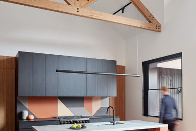 Inspiration for a contemporary kitchen in Melbourne with an integrated sink, flat-panel cabinets, black cabinets, concrete benchtops, terra-cotta splashback, black appliances, medium hardwood floors, with island and black benchtop.