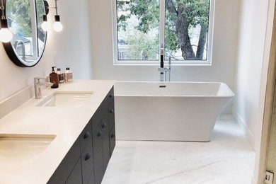 Mid-sized minimalist master porcelain tile and white floor freestanding bathtub photo in Calgary with flat-panel cabinets, black cabinets, gray walls, an undermount sink, quartzite countertops and white countertops