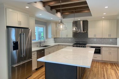 Inspiration for a mid-sized craftsman l-shaped medium tone wood floor, yellow floor and exposed beam eat-in kitchen remodel in San Francisco with a single-bowl sink, shaker cabinets, beige cabinets, quartz countertops, gray backsplash, ceramic backsplash, stainless steel appliances, an island and white countertops