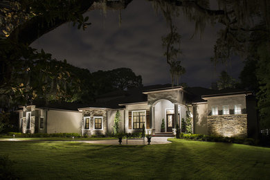 Photo of a large transitional one-storey stucco beige house exterior in Tampa with a shingle roof and a gable roof.