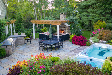Example of a mid-sized classic backyard stone patio design in New York with a fireplace and a pergola