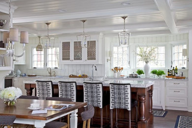 Example of a mid-sized transitional u-shaped dark wood floor and brown floor eat-in kitchen design in Other with white cabinets, white backsplash, wood backsplash, stainless steel appliances, an island, gray countertops, a farmhouse sink, recessed-panel cabinets and marble countertops